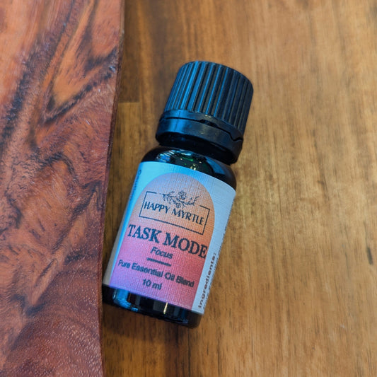 Small bottle of 'Task Mode' essential oil blend on a wooden surface used for focus
